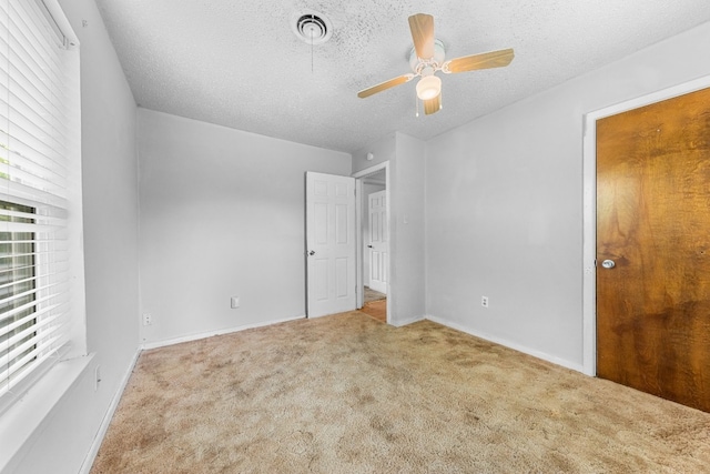 unfurnished bedroom featuring light colored carpet, ceiling fan, and a textured ceiling