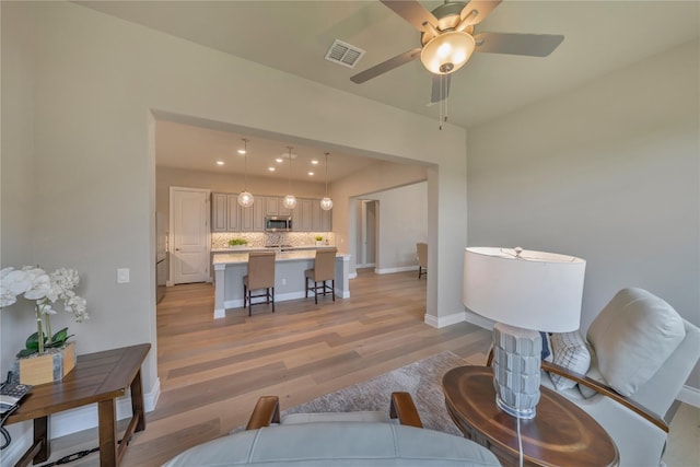 living room with ceiling fan and light hardwood / wood-style flooring