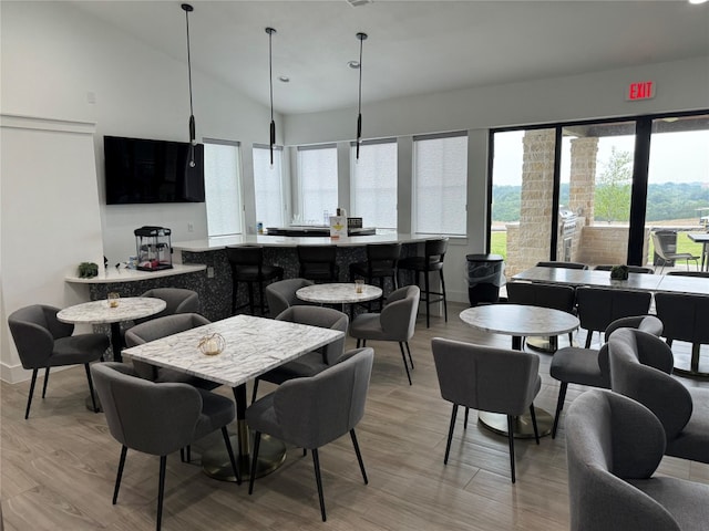 dining area with light hardwood / wood-style floors and high vaulted ceiling