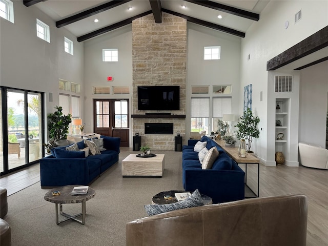 living room featuring a fireplace, a wealth of natural light, hardwood / wood-style flooring, beam ceiling, and high vaulted ceiling