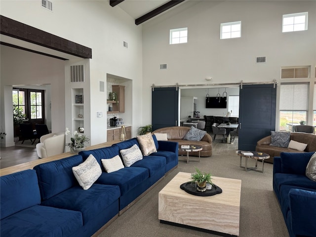 carpeted living room featuring beam ceiling, high vaulted ceiling, and a barn door