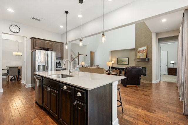 kitchen with a kitchen bar, appliances with stainless steel finishes, sink, a center island with sink, and hanging light fixtures