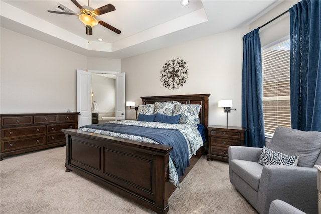 carpeted bedroom featuring a raised ceiling and ceiling fan