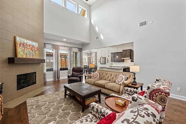 living room with dark hardwood / wood-style floors, a towering ceiling, and a fireplace