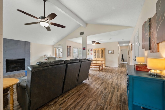 living room featuring vaulted ceiling with beams, a fireplace, dark wood-type flooring, and ceiling fan