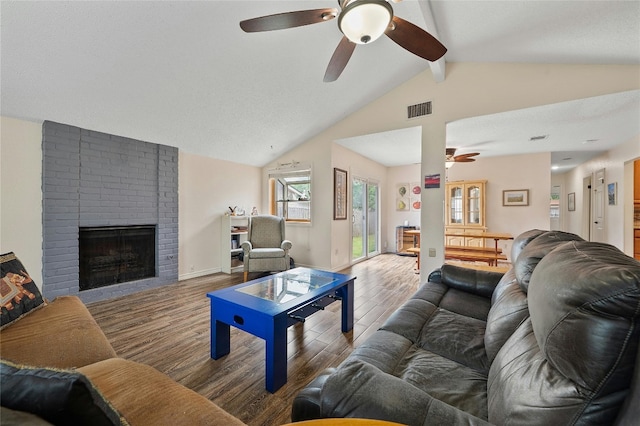 living room with hardwood / wood-style floors, vaulted ceiling with beams, a brick fireplace, and ceiling fan