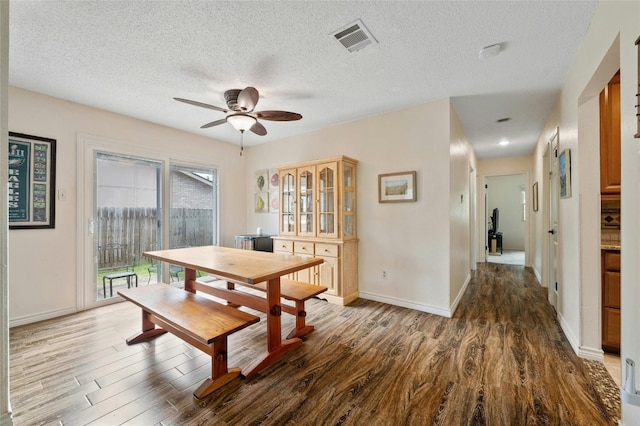 dining room with dark hardwood / wood-style floors, ceiling fan, and a textured ceiling