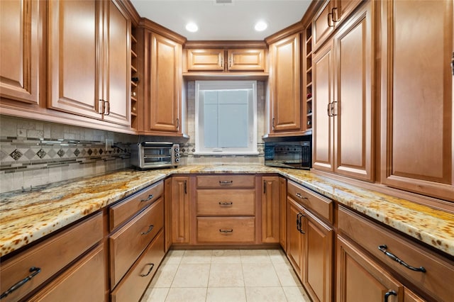 kitchen featuring decorative backsplash, light stone counters, and light tile patterned floors