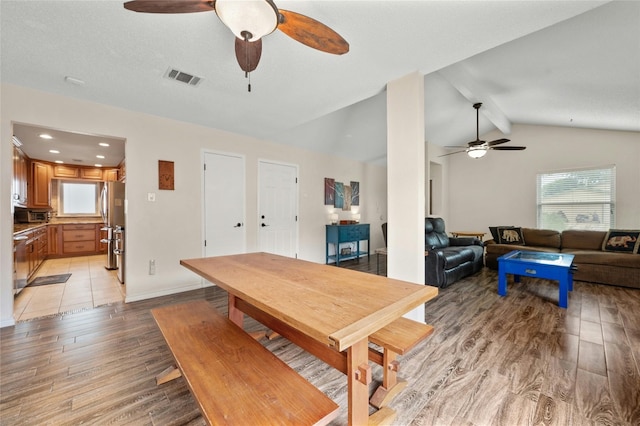 dining room featuring ceiling fan, lofted ceiling with beams, and light wood-type flooring