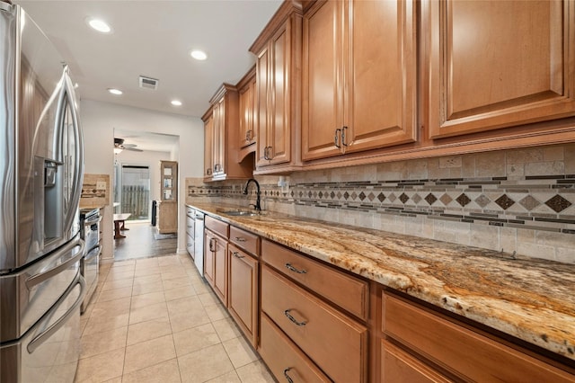 kitchen featuring appliances with stainless steel finishes, light stone counters, ceiling fan, sink, and light tile patterned floors