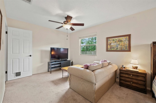 carpeted living room featuring ceiling fan and a textured ceiling