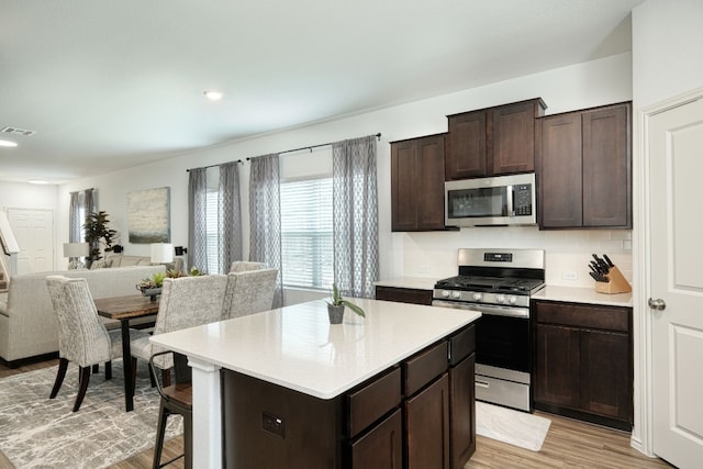 kitchen featuring dark brown cabinetry, light wood-type flooring, appliances with stainless steel finishes, and a kitchen island