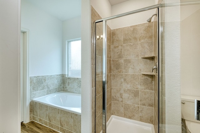 bathroom featuring toilet, hardwood / wood-style floors, and plus walk in shower