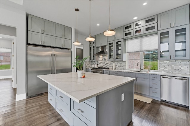 kitchen with a center island, sink, ventilation hood, decorative light fixtures, and appliances with stainless steel finishes