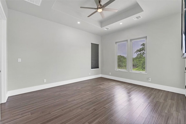 unfurnished room featuring baseboards, dark wood-style floors, a ceiling fan, visible vents, and a raised ceiling