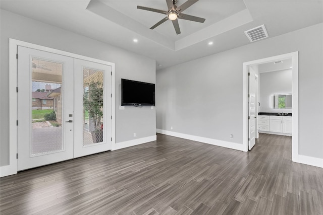 unfurnished living room featuring ceiling fan, a raised ceiling, dark wood-type flooring, and french doors