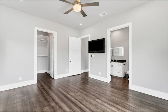 unfurnished bedroom featuring dark hardwood / wood-style flooring, ensuite bathroom, a spacious closet, and ceiling fan