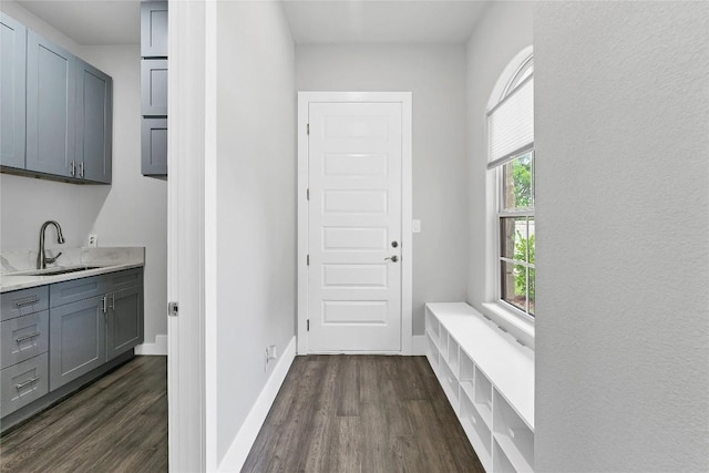 mudroom featuring dark wood-style flooring, baseboards, and a sink