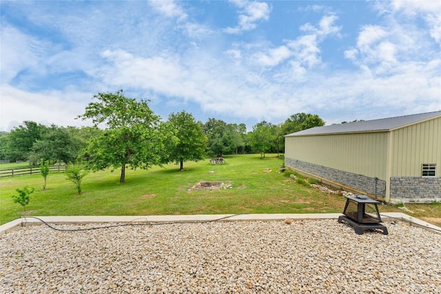 view of yard featuring an outbuilding, an outdoor fire pit, and fence