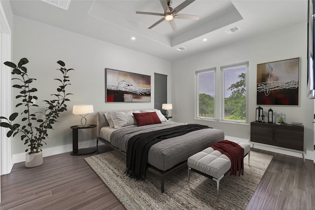 bedroom with a raised ceiling, ceiling fan, and dark hardwood / wood-style floors