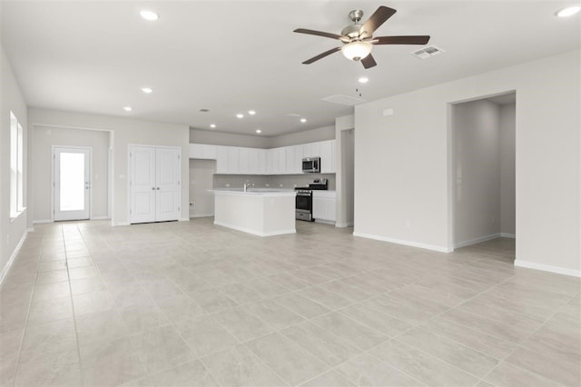 unfurnished living room featuring ceiling fan, sink, and light tile patterned floors