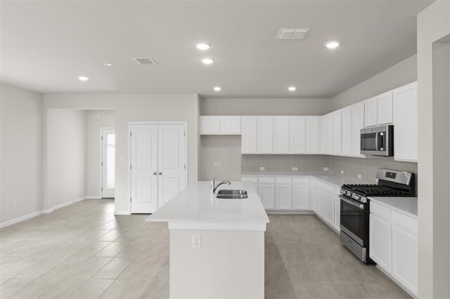 kitchen featuring white cabinetry, sink, a kitchen island with sink, stainless steel appliances, and decorative backsplash