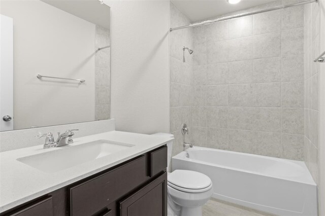 full bathroom featuring vanity, tiled shower / bath combo, and toilet