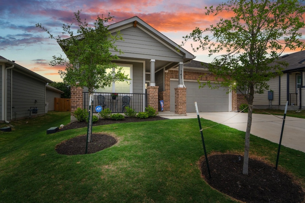 view of front of home with a porch, a yard, and a garage