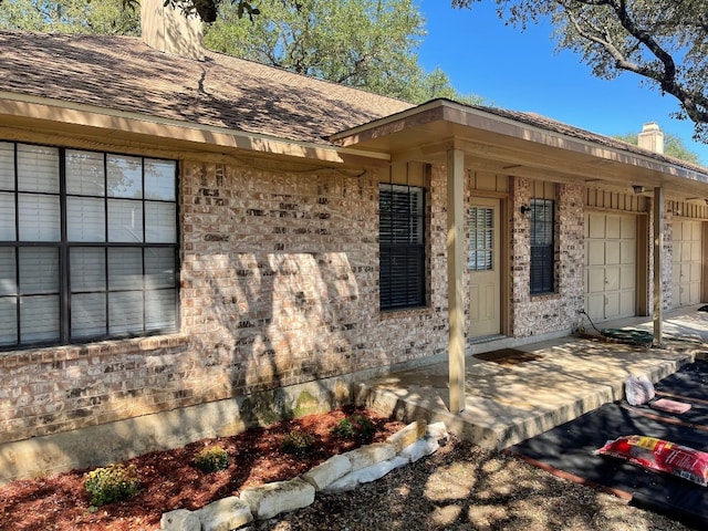 view of exterior entry with a porch and a garage