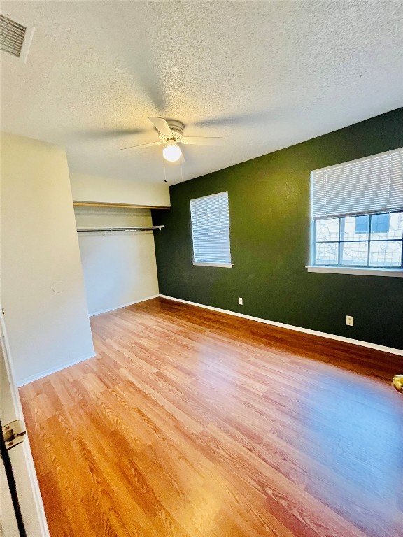 unfurnished bedroom featuring ceiling fan, a textured ceiling, and light wood-type flooring