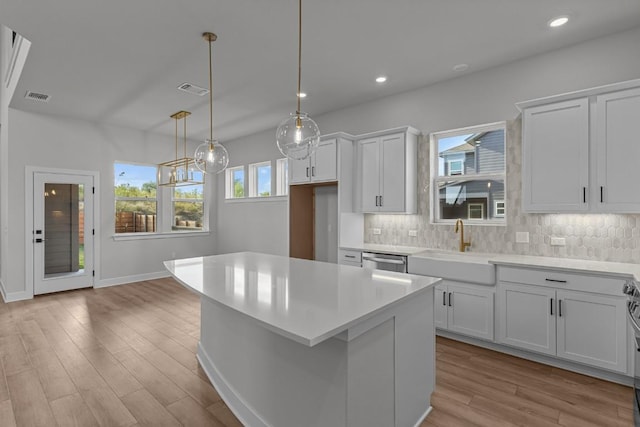 kitchen with white cabinets, tasteful backsplash, a kitchen island, and sink