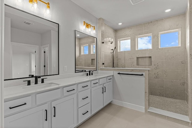 bathroom featuring tile patterned flooring, vanity, and a tile shower