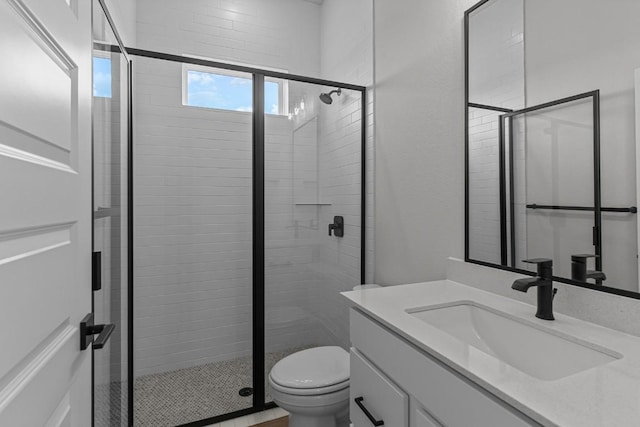 bathroom featuring vanity, toilet, and a shower with shower door