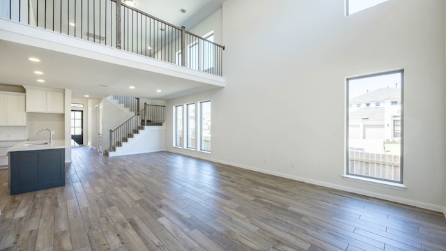 unfurnished living room with a towering ceiling, hardwood / wood-style floors, and sink