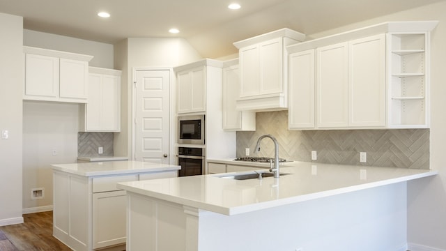 kitchen with white cabinets, kitchen peninsula, tasteful backsplash, appliances with stainless steel finishes, and dark hardwood / wood-style flooring