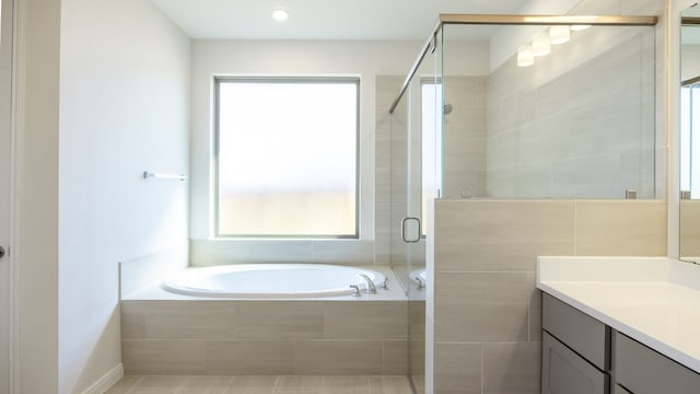 bathroom with a healthy amount of sunlight, separate shower and tub, and vanity