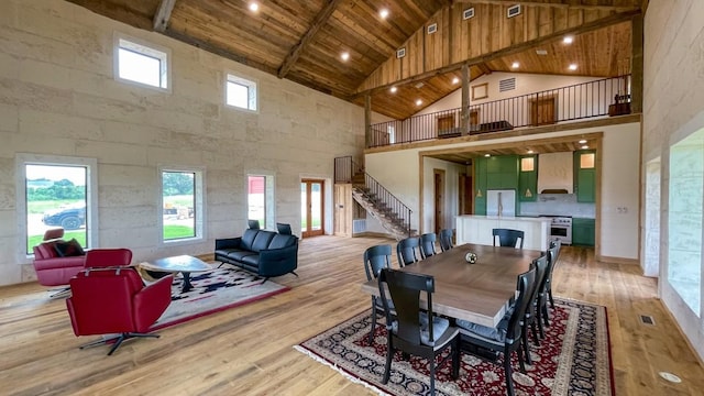 dining room featuring beam ceiling, light hardwood / wood-style flooring, high vaulted ceiling, and wooden ceiling