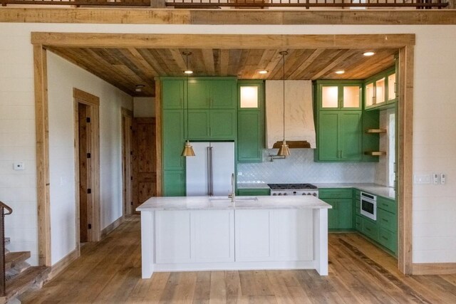 kitchen with stainless steel appliances, green cabinets, and light hardwood / wood-style floors