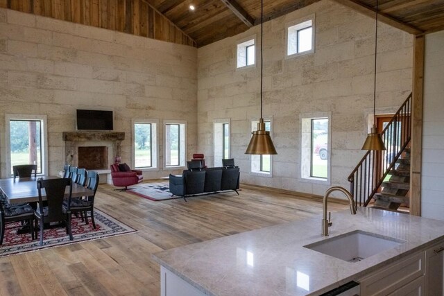 living room featuring wood ceiling, sink, high vaulted ceiling, and light hardwood / wood-style flooring