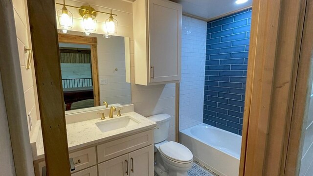 full bathroom with vanity, shower / bath combination, tile walls, and toilet