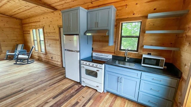 kitchen featuring sink, light hardwood / wood-style flooring, range hood, wood walls, and white appliances