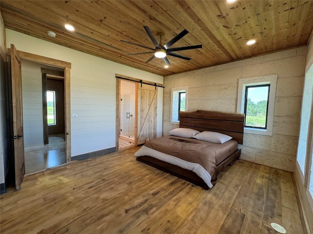 bedroom featuring hardwood / wood-style floors, a barn door, ceiling fan, and wood ceiling