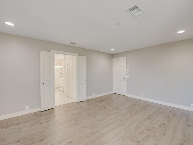 empty room with light wood-type flooring, visible vents, and baseboards