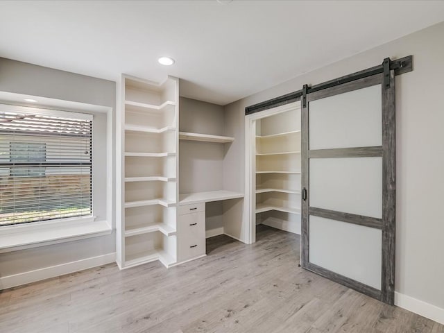 interior space with light wood finished floors and a barn door