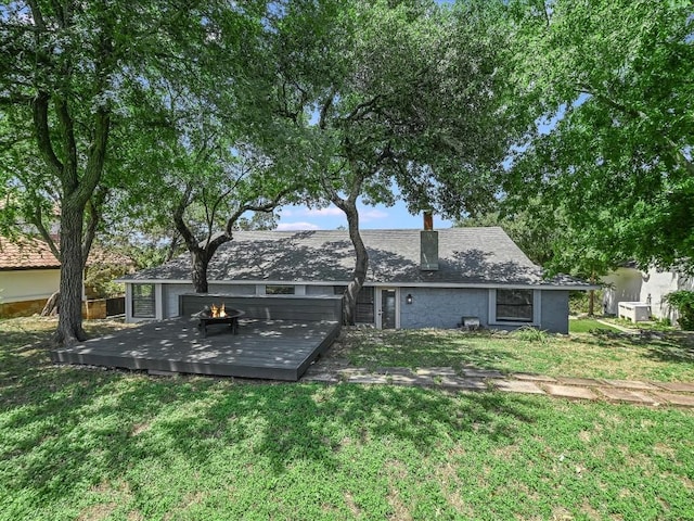 back of property featuring a yard, a chimney, and a wooden deck