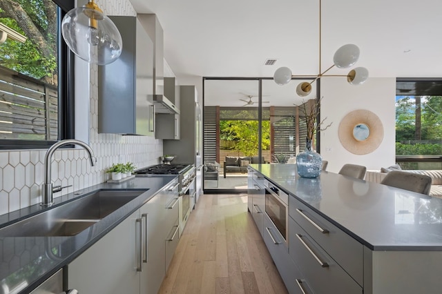 kitchen featuring decorative backsplash, gray cabinets, light hardwood / wood-style floors, and sink