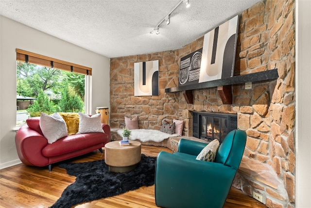 living room featuring hardwood / wood-style flooring, a fireplace, a textured ceiling, and track lighting