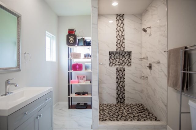 bathroom with a tile shower and vanity