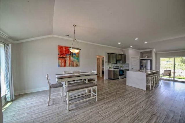 dining space with ornamental molding and light hardwood / wood-style floors