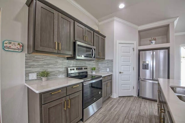 kitchen with appliances with stainless steel finishes, dark brown cabinets, light hardwood / wood-style floors, and crown molding